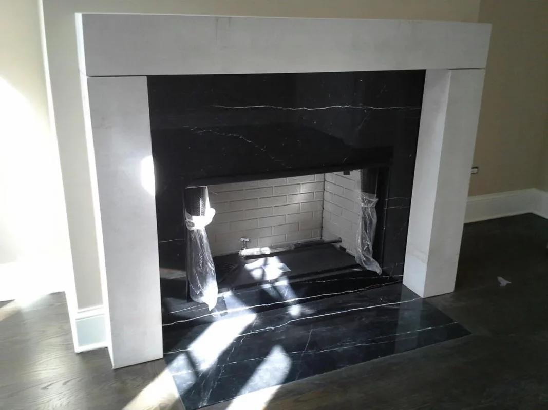 Black stone fireplace surround framed by a white mantel.