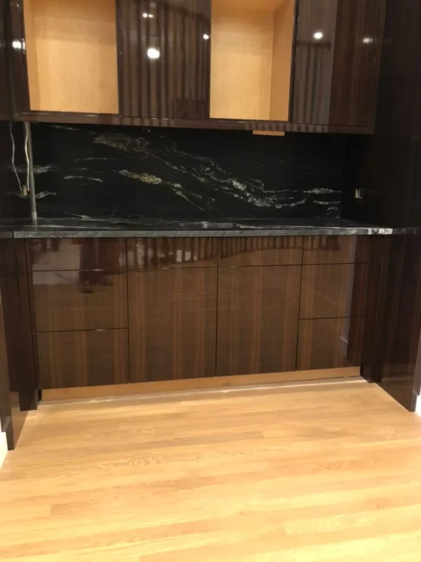 Dark wood cabinetry with a veined stone counter and backsplash.