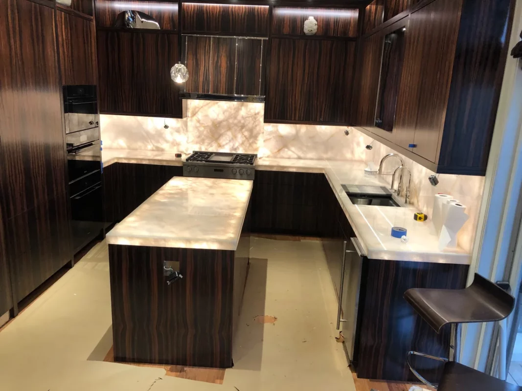 Dark wood kitchen remodel with a central island and continuous light stone surfaces.