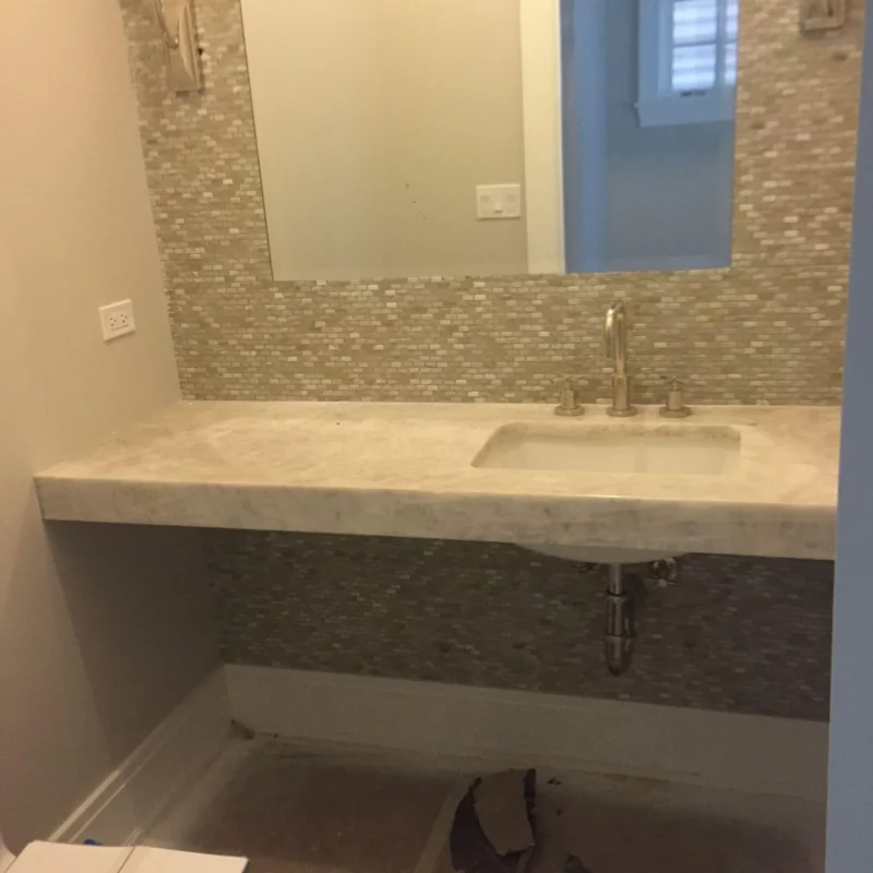 Bathroom remodel with a floating stone vanity and mosaic backsplash.