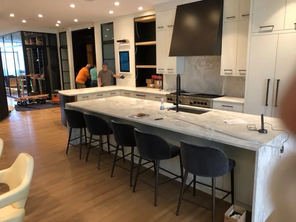 Modern kitchen remodel during final installation, with a waterfall island and full-height white cabinetry.