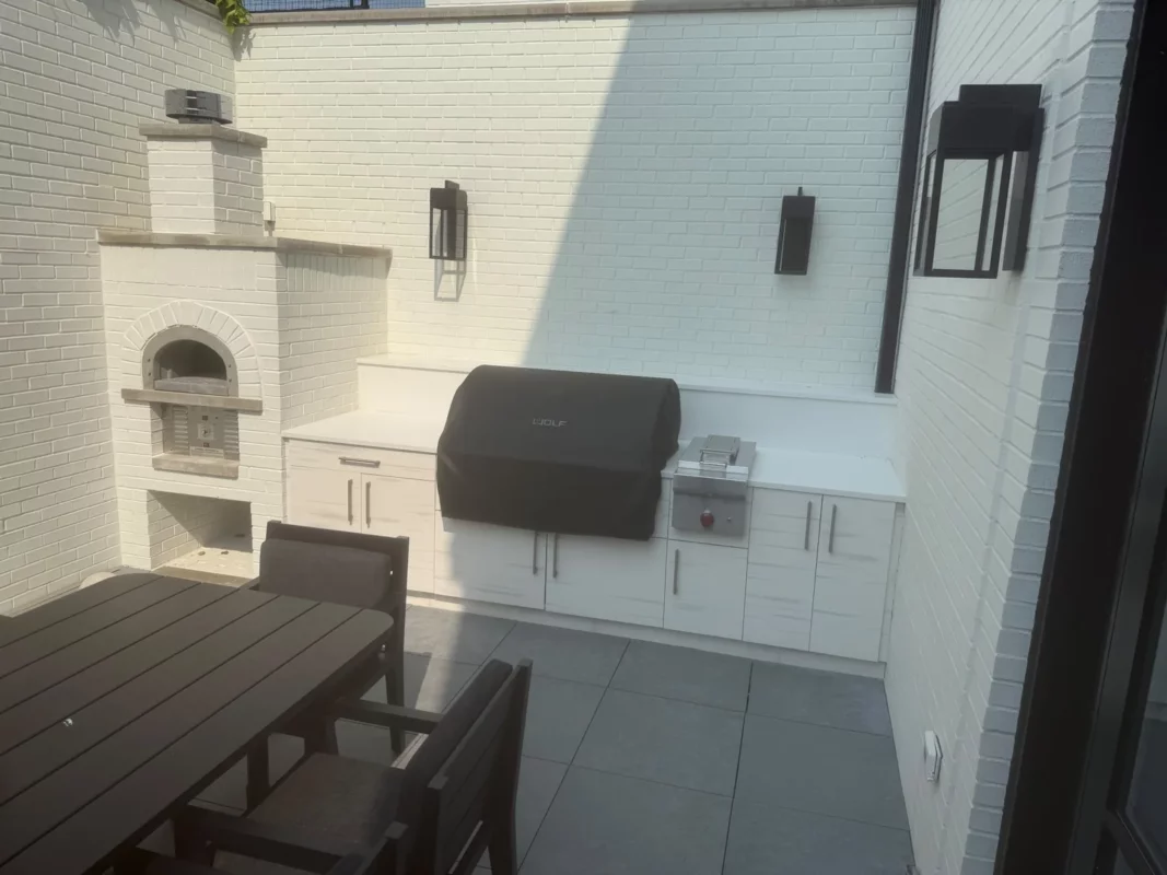 Outdoor kitchen and dining area with a built-in grill and fireplace.