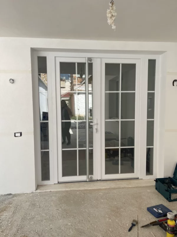 Replacement glazed double doors with matching sidelights and white frames, photographed while surrounding renovation work was still in progress.