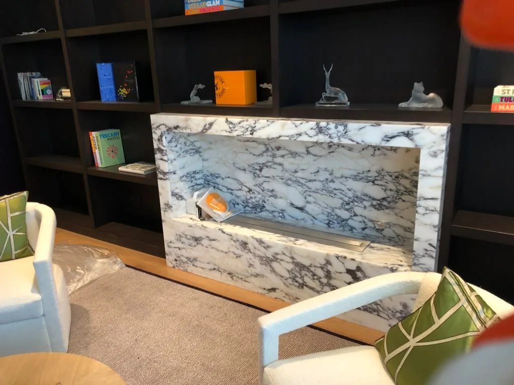 Veined stone feature fireplace set within dark built-in shelving.