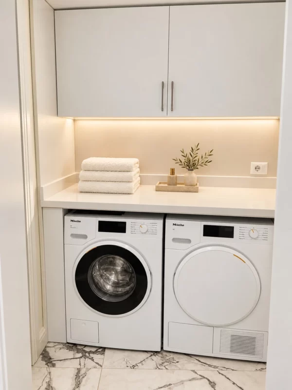 Miele washer and dryer beneath white cabinetry with neatly folded towels.